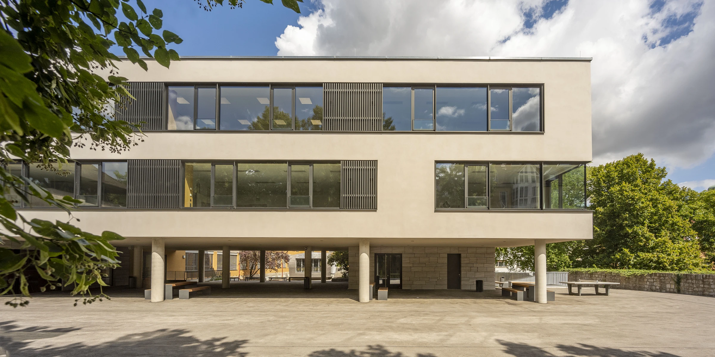 Schulbauerweiterung, auf Stützen, Fensterbänder in WDVS