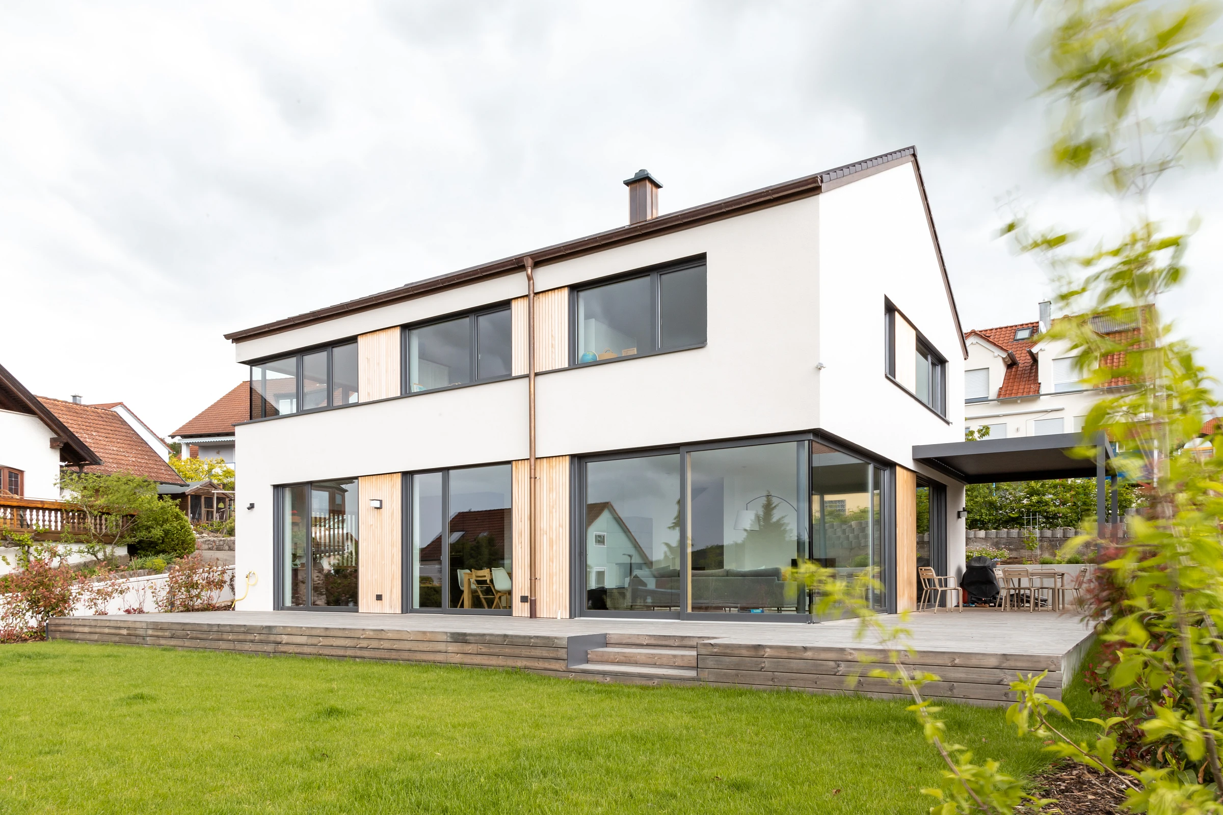 Außensicht Einfamilienhaus mit Putzfassade und Holzelementen