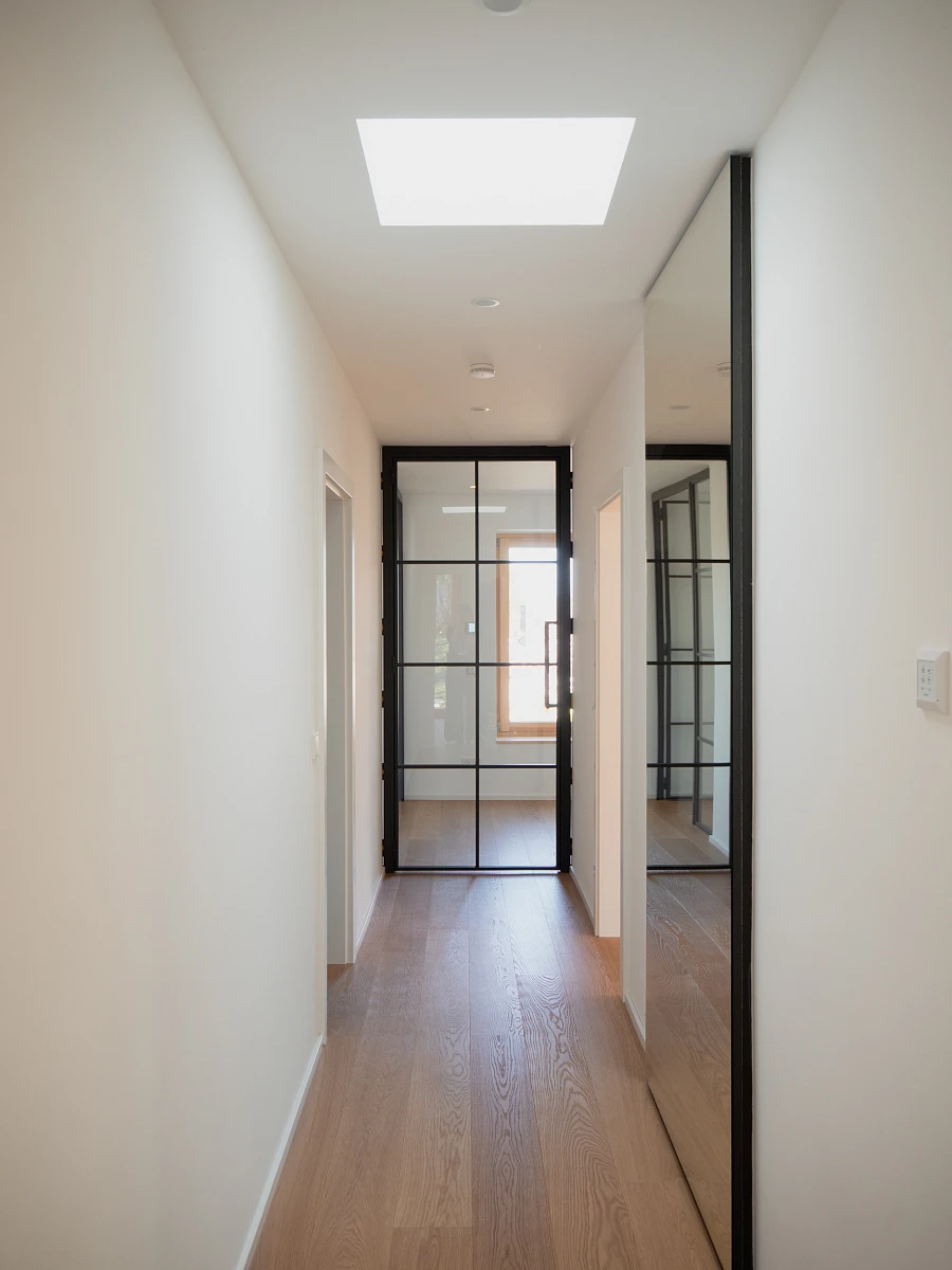 Innenansicht eines Flures mit Holzfußboden und Glastüre eines sanierten Einfamilienhauses