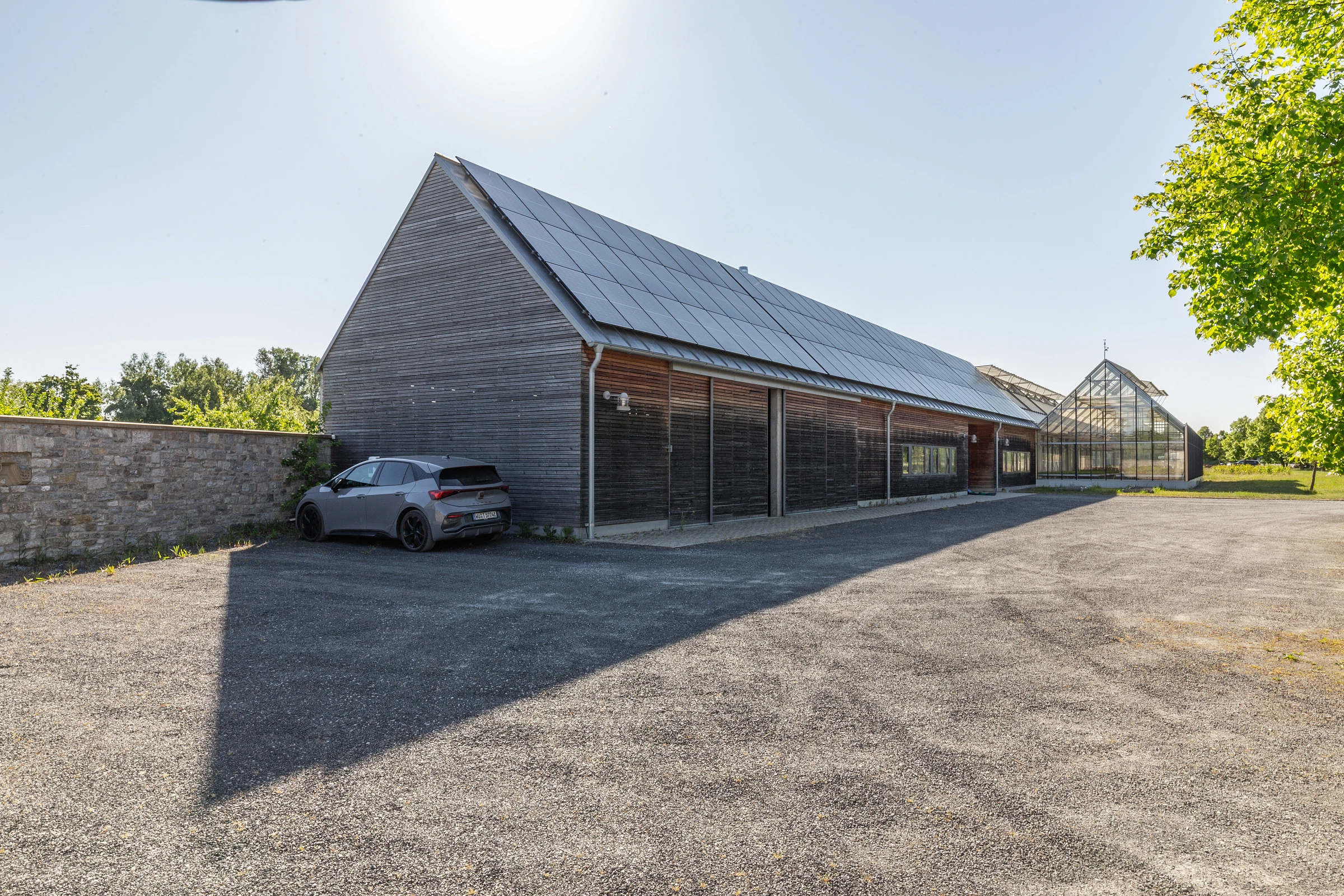 Außenansicht eines landwirtschaftlichen Gewächshauses als Anbau eines bestehenden Hofes